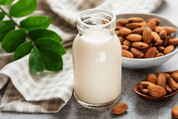 Lowest Carb Almond Milk: Sip Smart With This Keto Delight 2 A jar of almond milk accompanied by a bowl of almond nuts, showcasing the versatility of almonds as both a dairy alternative and a nutritious snack.