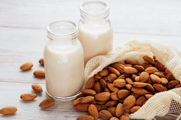 Lowest Carb Almond Milk: Sip Smart With This Keto Delight 3 Two jars featuring the lowest carb almond milk accompanied by a bowl of almond nuts.
