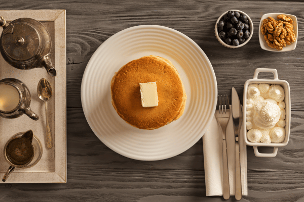 Top view of a coconut flour pancake topped with butter and different toppings and partners.