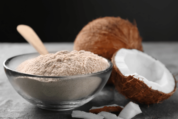 Transparent Bowl with Coconut Flour and Fresh Coconut on the Side.