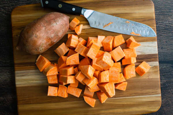 Skillet Sweet Potatoes: A Guide to Mouthwatering Perfection 7 Diced sweet potato with a knife on a wooden board