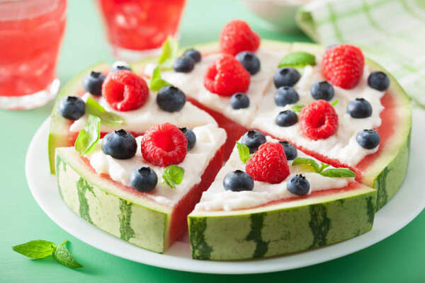 Irresistible Watermelon Pizza: A Sweet Twist on Tradition 2 Watermelon pizza slices topped with frosting, berries, and mint