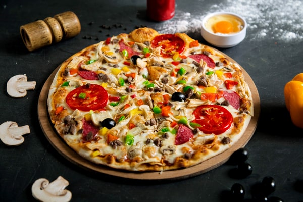 Cheesy pizza with mushrooms, black olives, tomatoes, and green pepper as toppings