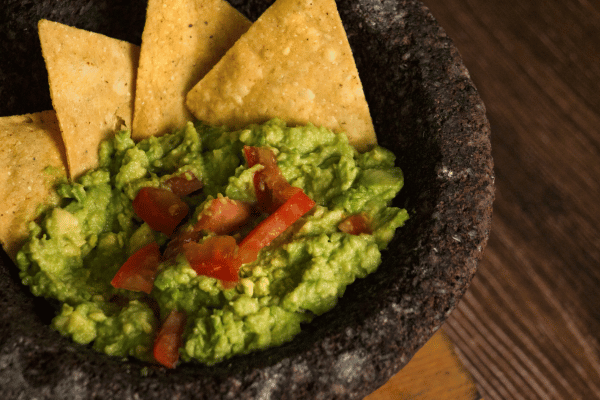 Molcajete with Guacamole on Wooden Table.