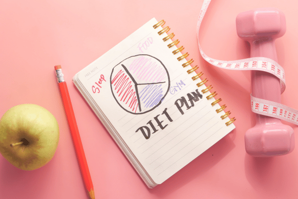 Plan with Almond Nuts, Dumbbells, and Apple on the Table.