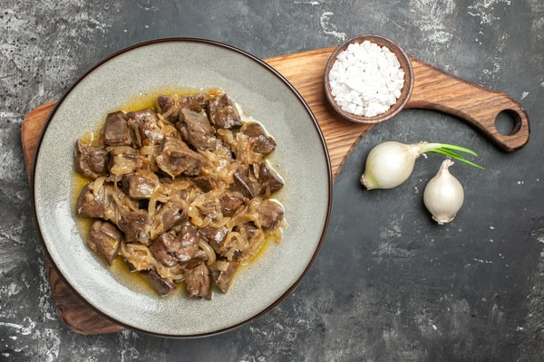 Keto Beef Stroganoff: Taste the Victory in Every Dish! 7 Beef stroganoff on a plate, placed on a wooden board along with a saucer of salt and white onions