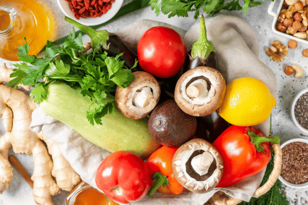 Fasting mimicking diet food. FMD to improve health and lose weight. A mix of vegetables, nuts, herbs, seeds, and mushrooms on a light gray background.
