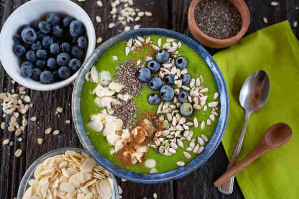 Low-carb green smoothie bowl with chia seeds, blueberries, and sliced almonds