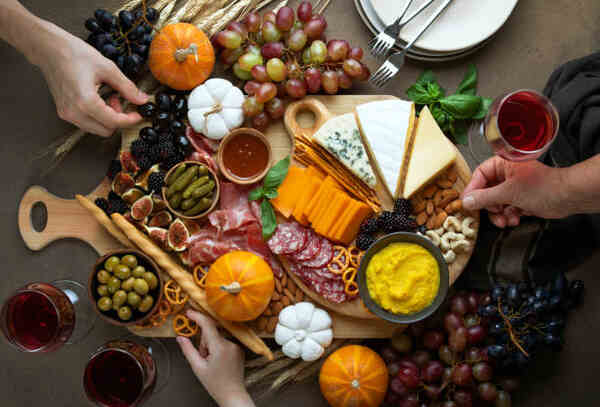 Keto Charcuterie Board Bliss: A Symphony of Low-Carb Taste 13 Hands arranging a charcuterie board with glasses of wine around