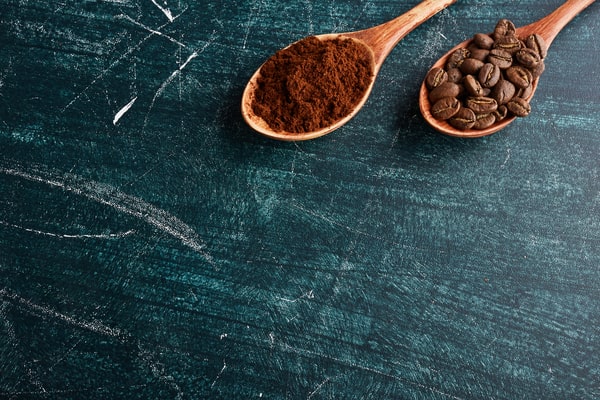 Fine coffee and whole coffee beans on wooden spoons