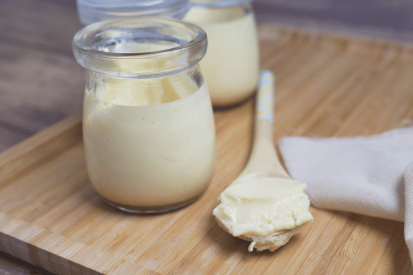 Beef Tallow in a jar with a portion scooped in a spoon that can be used for recipes.