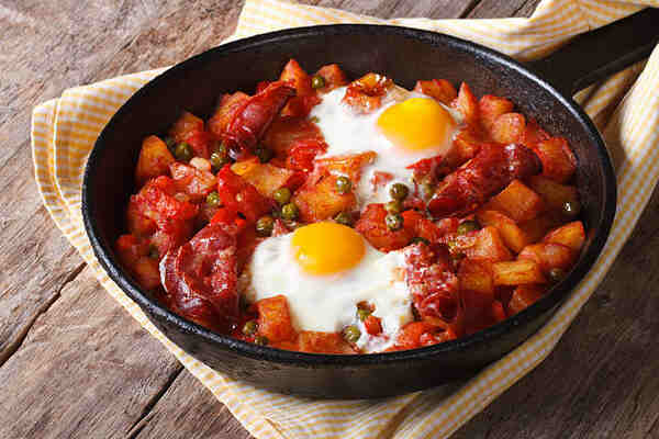 Flamenco eggs with potatoes, sausage, peppers, and peas