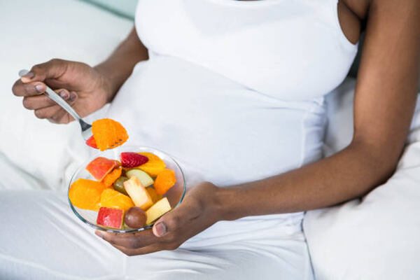 Can You Eat Pork While Pregnant? Master Prenatal Nutrition 12 A pregnant woman snacking on sliced fruits