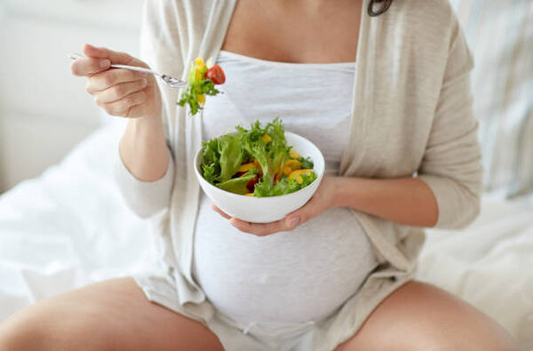 Can You Eat Pork While Pregnant? Master Prenatal Nutrition 5 A pregnant woman eating a bowl of vegetable salad