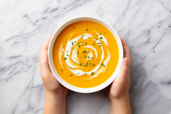 Keto Thickener: Low-Carb Substitutes for Culinary Mastery 3 A kid's hands holding a bowl of creamy pumpkin soup