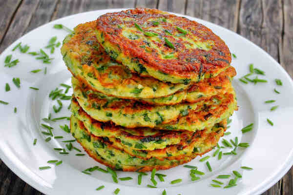 Keto Zucchini Fritters Recipe: Crispy Guilt-Free Indulgence 2 A stack of keto zucchini fritters garnished with chopped green onions