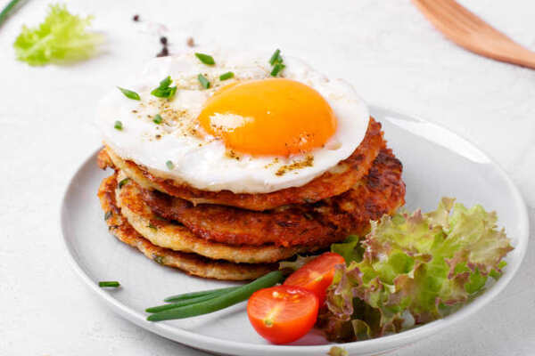 Keto Zucchini Fritters Recipe: Crispy Guilt-Free Indulgence 8 A stack of zucchini fritters with fried egg and vegetables