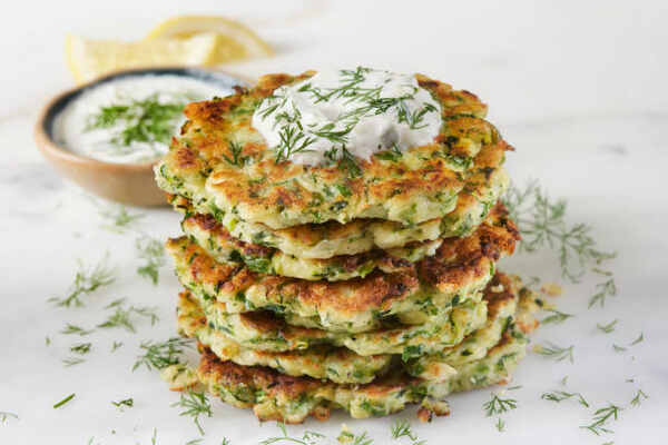 Keto Zucchini Fritters Recipe: Crispy Guilt-Free Indulgence 7 A stack of zucchini fritters with sour cream and herbs