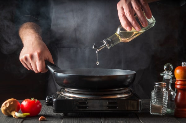 Is Safflower Oil Healthy? Learn the Facts You Can't Ignore! 5 A person pouring safflower oil into a pan with condiments and fresh ingredients on the side