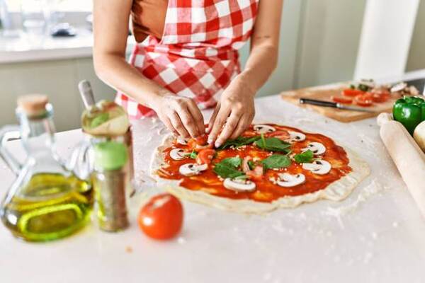 Keto Frozen Pizza: Indulge in Flavorful Crusts Guilt-Free 7 A woman putting toppings on a homemade pizza