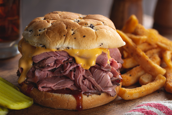 A double roast beef sandwich with melty cheese and BBQ sauce and side fries