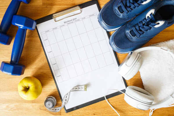 How to Lose 50 Pounds Safely: Your Comprehensive Guide! 11 A table of weekly workout plans with sneakers and dumbbells