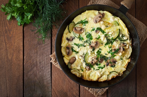 Mushroom Frittata Recipe: Quick and Easy Meal You’ll Love 2 A delicious frittata with mushrooms, and cheese, garnished with fresh herbs, served in a skillet on a rustic wooden table