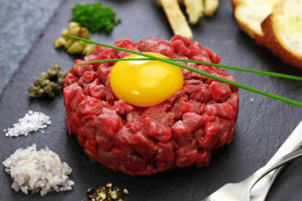 Perfect Steak Tartare: How to Make at Home 2 Delicious steak tartare topped with a fresh egg yolk and garnished with vibrant herbs