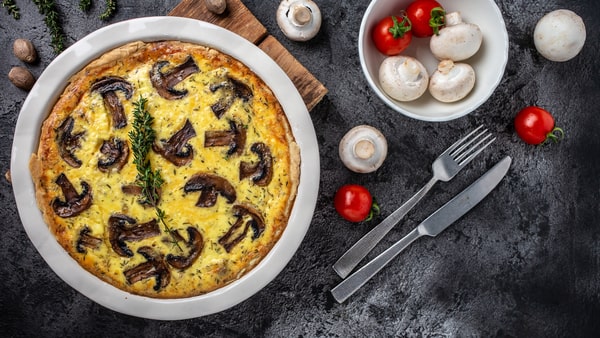Mushroom Frittata Recipe: Quick and Easy Meal You’ll Love 7 Traditional frittata mushrooms and cheese, garnished with fresh thyme, served in a baking dish with fresh ingredients and utensils on a dark textured background