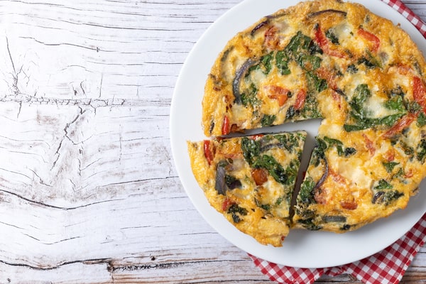 Mushroom Frittata Recipe: Quick and Easy Meal You’ll Love 8 An Italian frittata made with spinach, tomatoes, onions, and peppers, served on a white plate