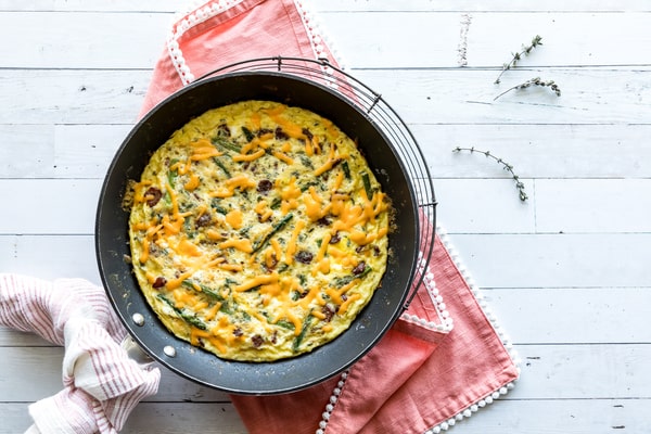 Mushroom Frittata Recipe: Quick and Easy Meal You’ll Love 9 A homemade frittata with bacon and asparagus, topped with melted cheese, cooling on a rack over a pink cloth on a white wooden table