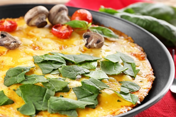 Mushroom Frittata Recipe: Quick and Easy Meal You’ll Love 10 A close-up of a tasty frittata topped with fresh spinach, mushrooms, and cherry tomatoes, served in a skillet with vibrant colors