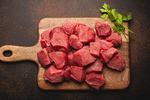 The Best Pork Cube Steak Recipe Using Slow Cooker 2 Raw meat chopped with bunch of fresh parsley on wooden cutting board.