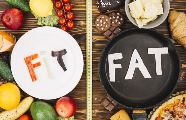 Signs of Gaining Muscle and Losing Fat: Quick and Easy Tips 2 A comparison of healthy foods spelling 'FIT' on a plate and unhealthy foods spelling 'FAT' in a frying pan, surrounded by various fruits, vegetables, and snacks