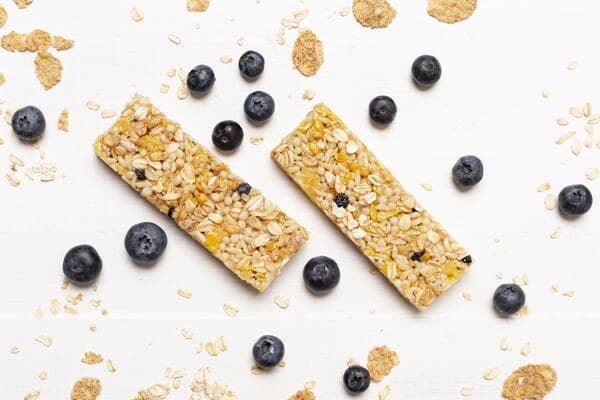 Quest Bars Keto: Your Go-to Snack for Weight Loss 5 Two granola bars with blueberries and oats, surrounded by scattered blueberries and oat flakes on a white surface