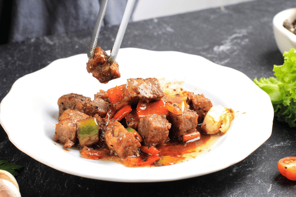 The Best Pork Cube Steak Recipe Using Slow Cooker 6 Diced beef on a plate with veggies and spices.