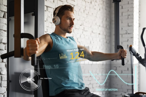 Signs of Gaining Muscle and Losing Fat: Quick and Easy Tips 4 A man working out on a chest press machine with headphones on, surrounded by digital health stats displaying heart rate, rep count, and range of motion