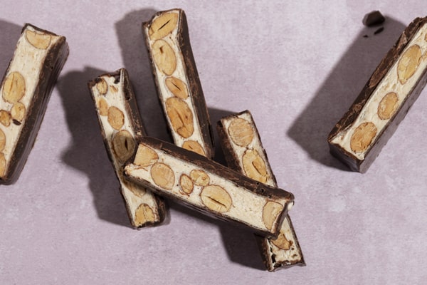 Quest Bars Keto: Your Go-to Snack for Weight Loss 4 A flat lay of chocolate-coated nougat bars with visible nuts inside, arranged on a light pink background