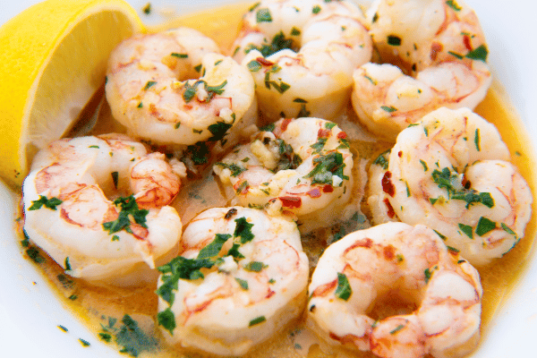 Keto Shrimp Scampi: Quick, Easy, & Low-Carb Recipe 6 Golden, perfectly cooked shrimp drizzled with zesty lemon sauce and garnished with fresh herbs.
