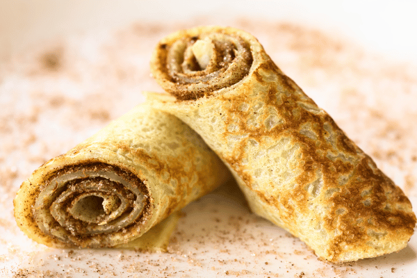 Trader Joe's Cauliflower Thins: Healthy Snack Hacks 6 Cinnamon Sugar Cauliflower Thins on a plate with a sprinkle of cinnamon powder