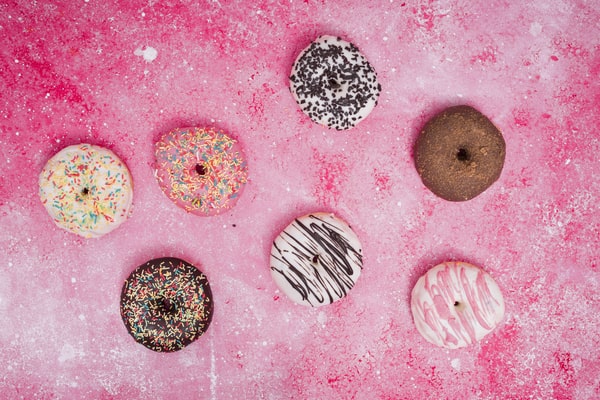 Quest Bars Keto: Your Go-to Snack for Weight Loss 8 Eight colorful donuts with various toppings and sprinkles, arranged on a vibrant pink background dusted with powdered sugar