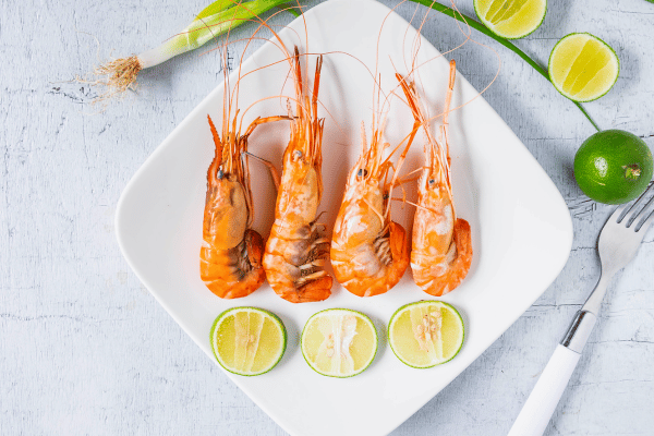 Keto Shrimp Scampi: Quick, Easy, & Low-Carb Recipe 7 A plate adorned with succulent cooked shrimp, surrounded by slices of vibrant lemon.