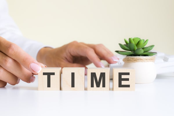 Signs of Gaining Muscle and Losing Fat: Quick and Easy Tips 7 A person's hand arranging wooden blocks that spell out 'TIME' on an office desk with a small potted plant in the background