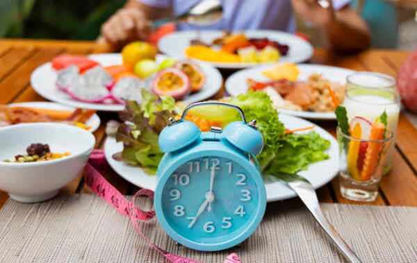 One Meal a Day: The Ultimate Guide to the OMAD Diet 2 A spread of healthy dishes behind an alarm clock