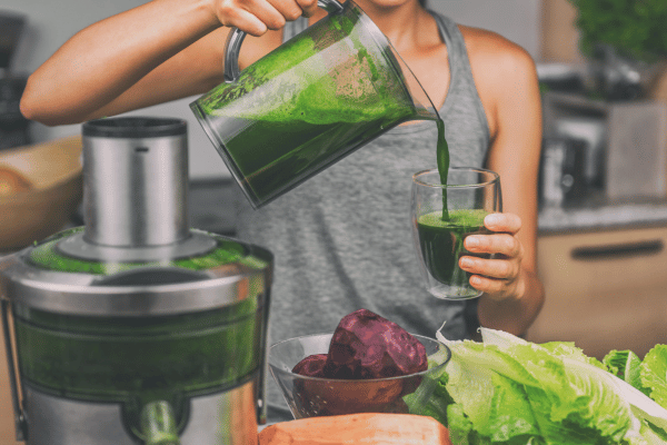 Low Carb Juicing: How to Make Tasty and Healthy Juices 3 A woman pours freshly blended vegetable and fruit juice into a glass.