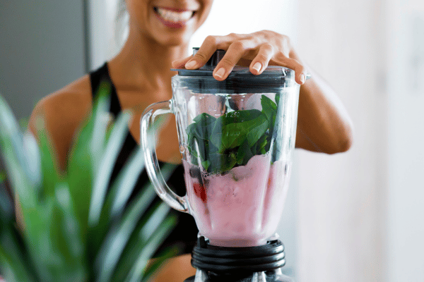 Low Carb Juicing: How to Make Tasty and Healthy Juices 16 A woman blending strawberries, berries, spinach, cucumber, and lime.