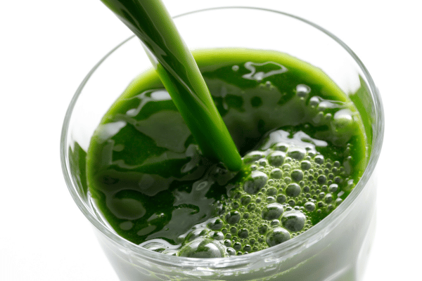 Low Carb Juicing: How to Make Tasty and Healthy Juices 4 Pouring a glass of green juice into another glass.