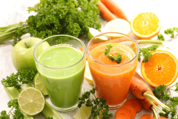 Low Carb Juicing: How to Make Tasty and Healthy Juices 5 Two glasses of juice: one green with apple, leafy greens, and lime; the other orange with carrots and orange.