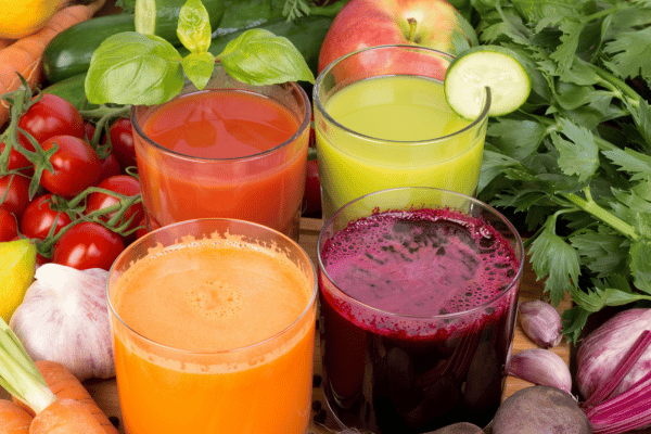 Low Carb Juicing: How to Make Tasty and Healthy Juices 6 Four glasses of juice: one with apples and greens, one with carrots and oranges, one with beets and berries, one with pineapples and cucumbers.