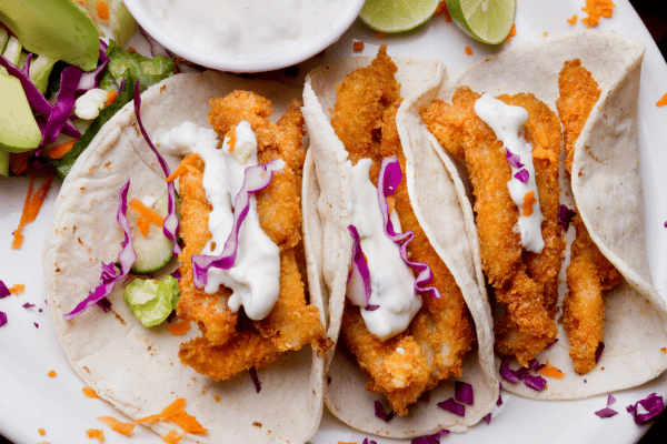 Keto Fish Tacos: The Ultimate Low Carb Recipe and Tips 10 Fish tacos with chips, salsa, beer, limes, avocado, and tartar sauce.